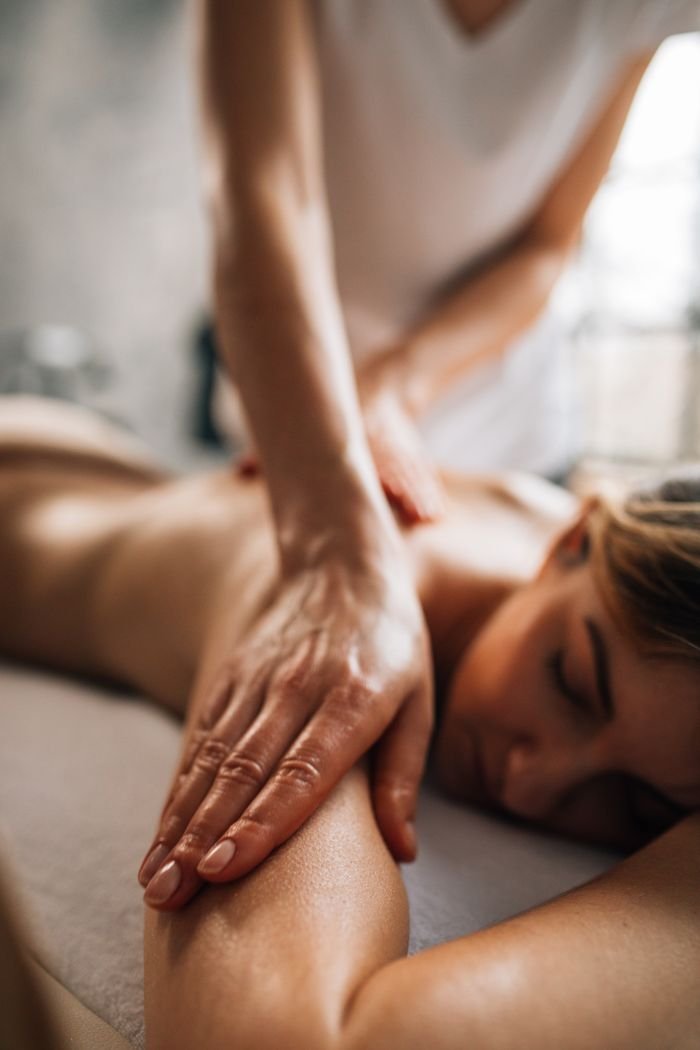 A woman enjoying a relaxing massage in a serene spa environment, promoting self-care and wellness.